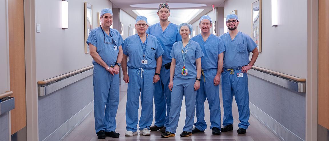 A dark-haired man and two women with long dark hair, all wearing blue Heartfelt Charity hospital scrubs, stand close together and smile thanks to the cancer fundraising donations Heartfelt Charity has received.